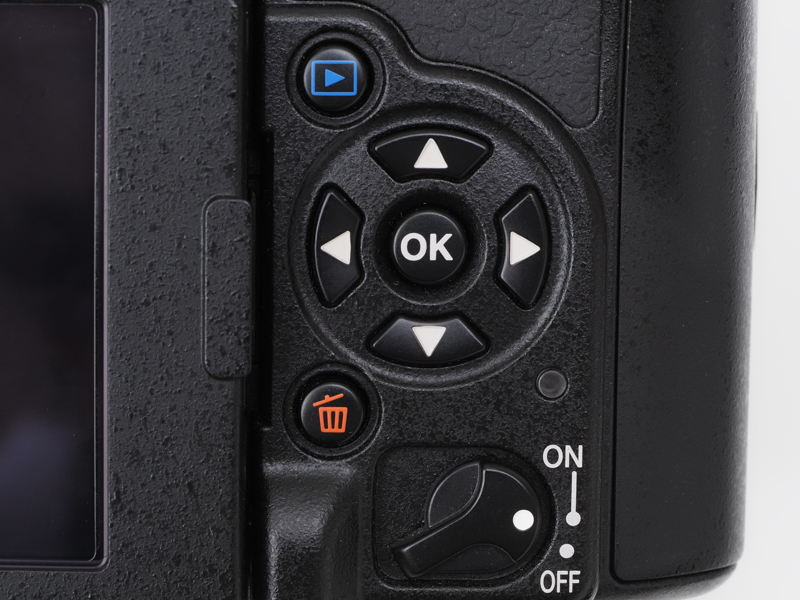 裏面ですね。最近流行りのグリグリはないです。十字ボタンを押してAFエリアを変更します。タッチパネル方式ならと思うのですが、光学ファインダー覗かないと、AFエリアの選択位置はわからないですからねえ。