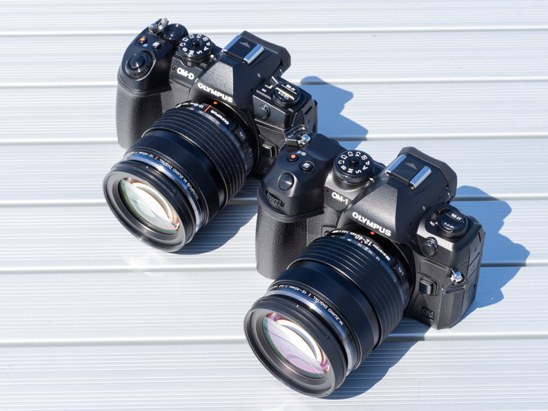 OM-1に装着したM.ZUIKO DIGITAL ED 12-40mm F2.8 PRO II（手前）と、E-M1 Mark IIIに装着したM.ZUIKO DIGITAL ED 12-40mm F2.8 PRO（奥）を並べて見比べる。その外観はほぼ同じだが、マウント部の焦点距離表記を大きな文字で読みやすくなるなど、細かな違いも見られる。