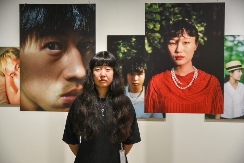 卞敏さん。会場をポートレート写真で埋め尽くしたい。天井から下げた2枚はそんな想いの結果らしい