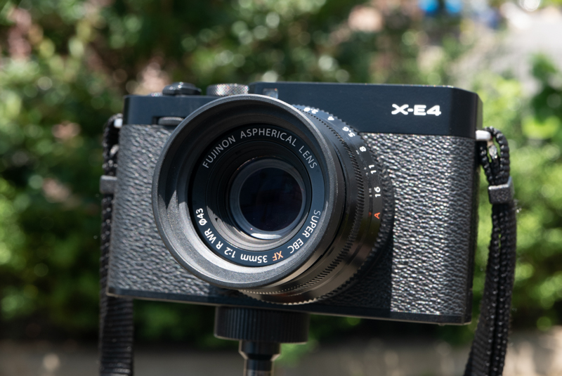 付属フードを装着。銘板の上部は影になった。小さくても遮光効果が高い。しかし前玉の下にはまだ直射光が当たったままだ。