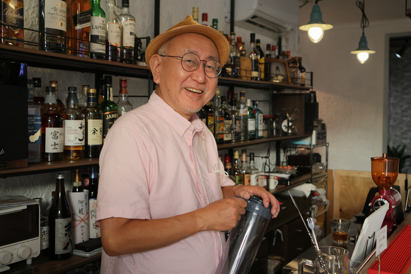 湘南の茅ヶ崎に8月に開店したばかりの音楽&写真バー「五月野」。元「アサヒカメラ」編集者の高畠保春さんが経営。西日がわずかに入る状態で撮影しています。ミックス光になりましたが良い感じで、階調が繋がりました。「音楽と写真 五月野」：神奈川県茅ヶ崎市共恵1-6-22　JR茅ヶ崎駅徒歩5分<br>EOS R7　EF24mm F2.8 IS USM（F3.2・1/40秒）ISO 400