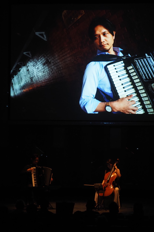 投影された写真の前で演奏する2人