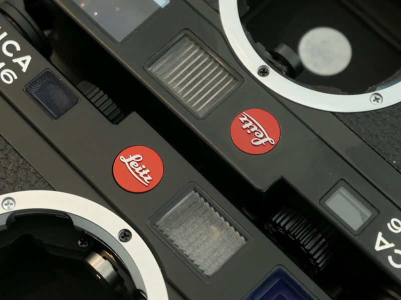 新旧Leitzバッジは微差。以前見学した本社カスタマーケアでは、調整時にLeicaバッジを牛乳瓶のフタのように剥がし、作業後に新しいものを貼り付けていたので、旧のほうは必ずしも本体の年代と紐付かないかもしれない