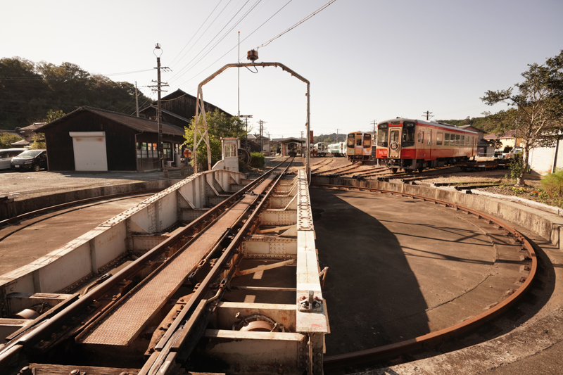 天浜線は全長67.7kmの路線ですが、そのなかに36件にも及ぶ登録有形文化財があります。とくに天竜二俣駅に隣接する旧機関区周辺は、文化財の宝庫なのです。こちらは、昭和15年製のターンテーブル（機関車転車台）です。もともとはSLがバンバン走っていた路線なので、牽引する蒸気機関車の進行方向を変えたり、隣接する扇形庫に留置するためのターンテーブルが大活躍していました。当時は手動でしたが、現在は電動化されています。背後には機関車扇形車庫も健在です。<br>ソニーα7R IV　FE16-35mm F2.8 GM （17mm） 絞り優先オート （F6.3、1/800秒）ISO 400 WB:日陰　<a href="https://goo.gl/maps/AmP7bGafHNVNcpePA" class="n" target="_blank">[Google Maps]</a>