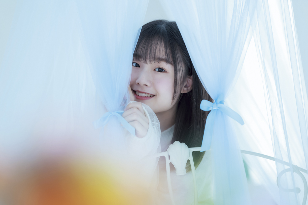 天蓋の隙間から顔を出してもらいました。窓からの光もきれいにぼけていて、画質がとってもきれい。4,000KのWBで青みを強め、お花の前ボケでオレンジ色をポイントに使いました<br><span class="fnt-85">キヤノン EOS R6 Mark II／RF135mm F1.8 L IS USM／135mm／マニュアル露出（F1.8、1/1,250秒）／ISO 400／WB：4,000K</span>