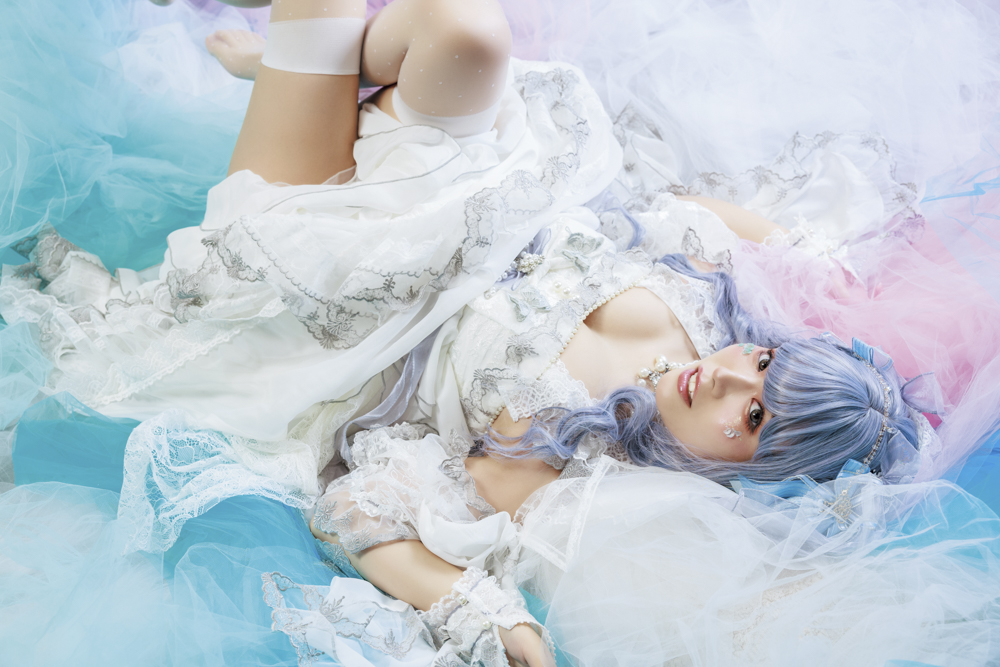 イメージしたのは舞い降りてきた天使。床にピンクと白、水色のチュールを敷き詰めて、その上に寝てもらった。スピードライトのセッティングは本文中のSCENE 1と同じ。表情が見える左サイドからカメラ目線を狙った<br><span class="fnt-85">キヤノン EOS R6 Mark II／RF24-70mm F2.8 L IS USM／41mm／マニュアル露出（F5.6、1/160秒）／ISO 400／WB:5,250K／EL-5×3灯</span>