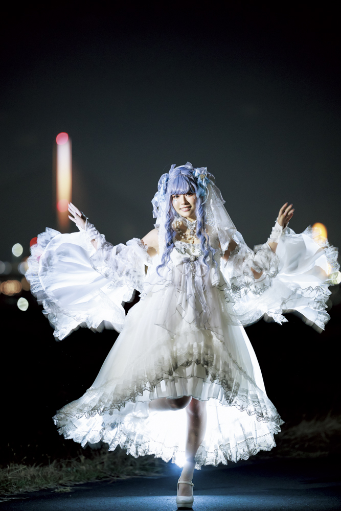 背後からのフラッシュ光が白いドレスを浮かび上がらせてくれた。美しく広がったドレス形状を見せるため、腕を広げるポージングをお願いしている<br><span class="fnt-85">キヤノン EOS R6 Mark II／RF135mm F1.8 L IS USM／135mm／マニュアル露出（F1.8、1/50秒）／ISO 3200／WB：5,000K／EL-5×2灯</span>