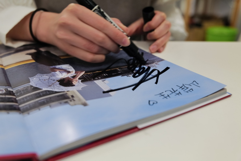 でき上がった2nd写真集にサインを入れてもらいながら当時を振り返る