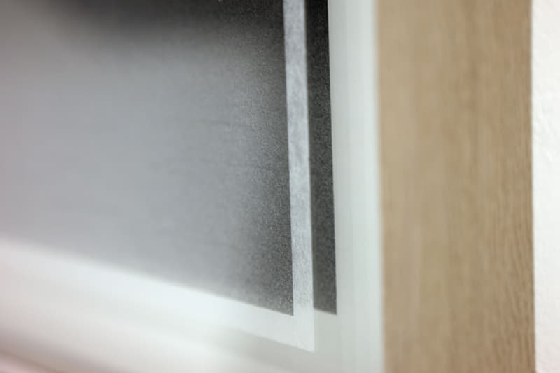 （左）世界最高と称されるわずか0.03mmの和紙に印刷されているため、一部は透過して二層目の和紙と重なる。（右）菅原さんがiPhoneのライトで照らしてくれた。木目が細やかで美しい和紙であることが分かる