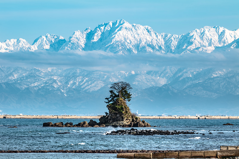 雨晴海岸は海越しの立山連峰を望むことができる大人気スポット。手前の女岩と剱岳が重なる位置から300mmの望遠で撮影した。細部まで解像した剱岳は圧巻だ。<br>ライカSL2／パナソニック LUMIX S 70-300mm F4.5-5.6 MACRO O.I.S.／300mm／マニュアル露出（F16、1/30秒）／ISO 100／WB：オート