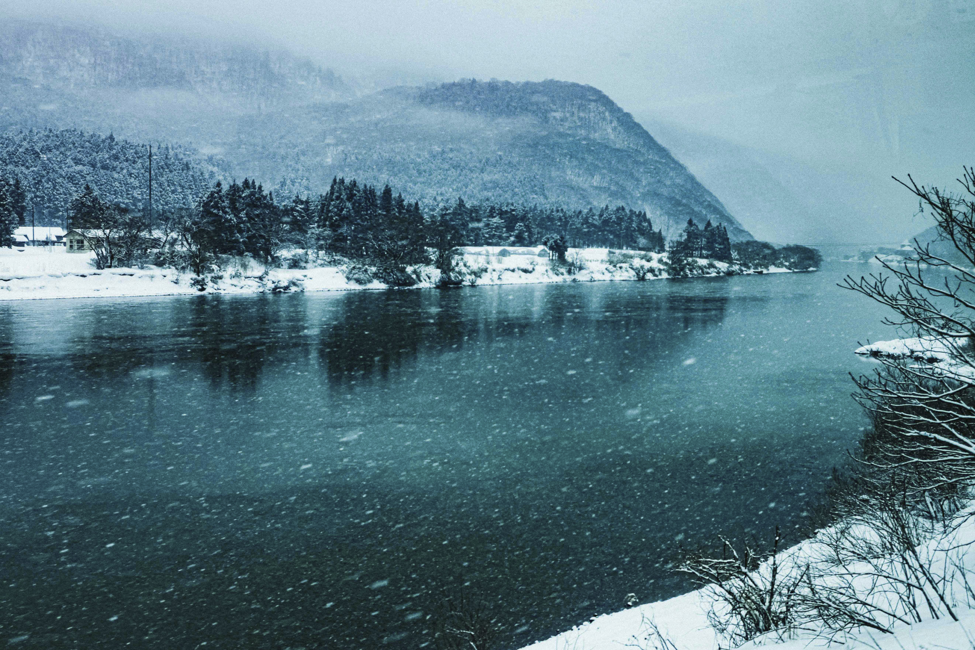 山形でバスに揺られる。山間部に進むにつれて雪は強まり、勢いよく流れていった。ファインダーが見やすいので、車窓からでもピントを確認しやすい<br><span class="fnt-85">EOS R8／RF35mm F1.8 MACRO IS STM／35mm／マニュアル露出（F5.6、1/500秒）／ISO 200／WB: 4300K</span>
