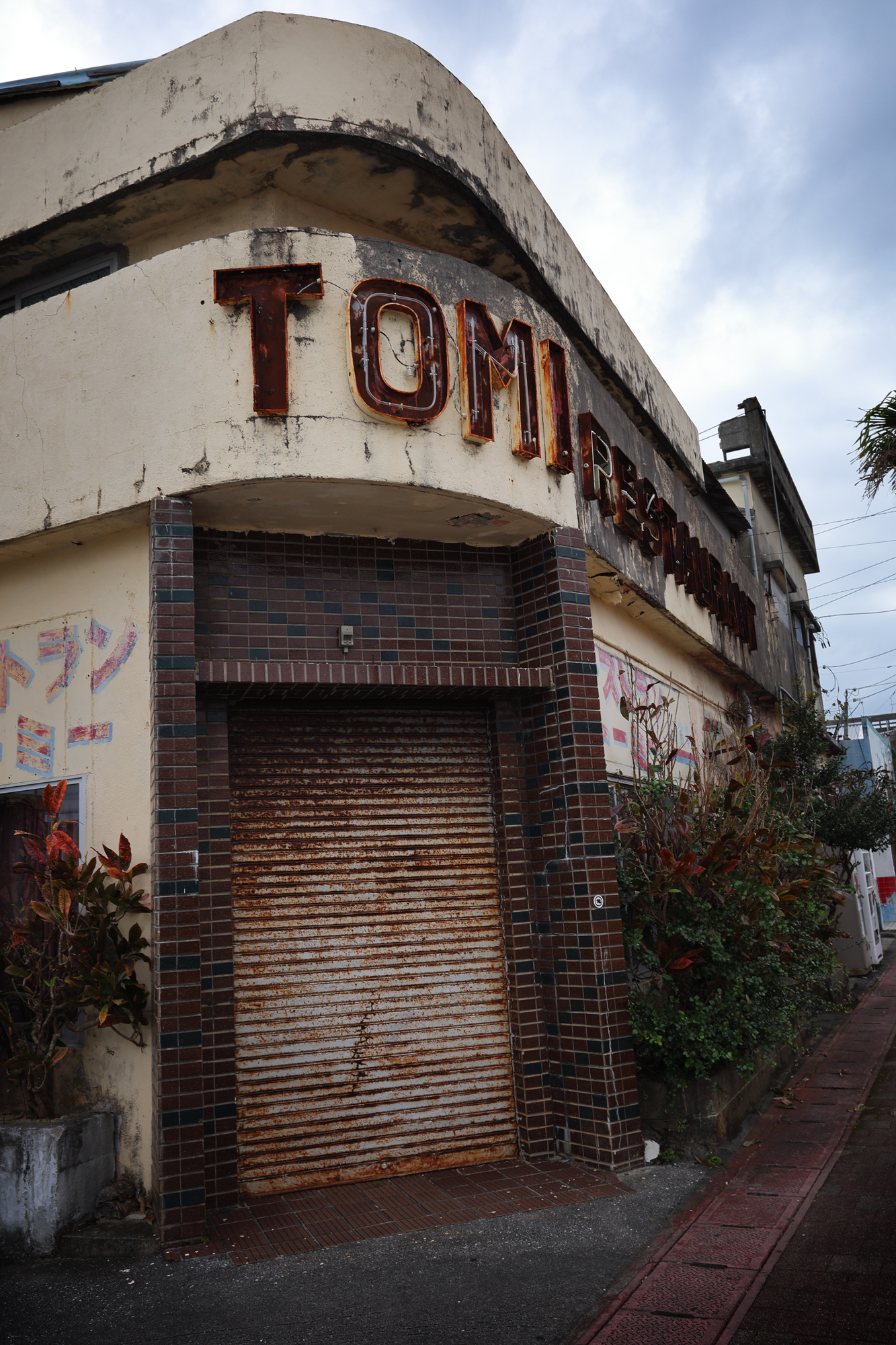 アメリカ文化を色濃く感じられる金武町。老朽化した建物が多く人もまばらだが、それがかえって独特の雰囲気を醸し出していた。曇天の空が階調豊かに描かれて、怪しげに仕上がった<br><span class="fnt-85">EOS R8／RF15-30mm F4.5-6.3 IS STM／28mm／プログラムAE（F9、1/125秒、-0.3EV）／ISO 100／WB:オート</span>