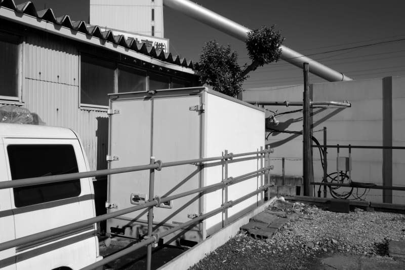 セメント工場。奇妙な世界観を感じたので撮影してみました。撮影時から筆者にはモノクロな光景に見えたので、フィルムシミュレーションをACROSに設定しました。コントラストが高い条件ですが、ハイエストライトからディープシャドーまでの繋がりは見事です。<br>X-E4／XF18mmF2 R／絞り優先オート（F8・1/1,800秒）／ISO400