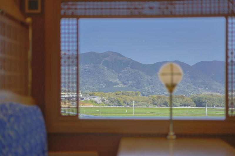 のどかな車窓風景がどんな場所から見えた景色なのか表現したくて、窓枠を入れて撮影。HDR動体優先なら風景は流れず窓枠も暗くならない。明るい旅のシーンを表現できた<br><span class="fnt-85">EOS R8／RF50mm F1.8 STM／50mm／マニュアル露出（F1.8、1/4,000秒）／ISO 800／WB：オート</span>