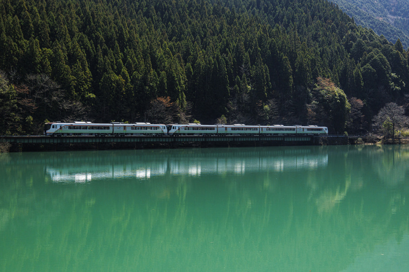 有名撮影地の下原ダムはどんな焦点距離でも絵になる。デビュー間もないHC85系の存在とダムの湖面をバランス良く収めたくて、迷わず標準ズームレンズを選択した<br><span class="fnt-85">EOS R8／RF24-105mm F4-7.1 IS STM／57mm／マニュアル露出（F6.3、1/1,000秒）／ISO 1250／WB：オート</span>