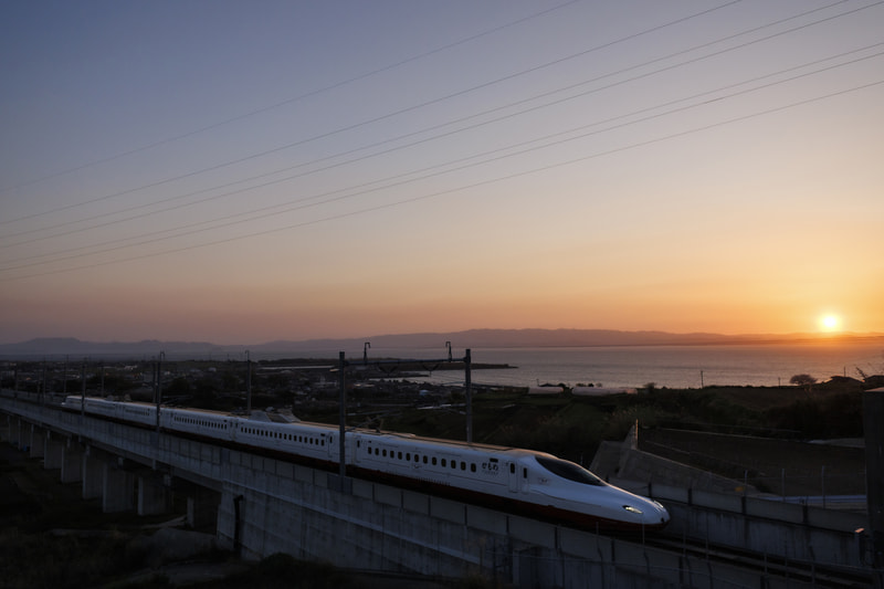 山並みに美しい夕日が落ちる寸前に西九州新幹線「かもめ」がやってきた。広角レンズにしたことで夕日が構図に収まり、車体も伸びやかに写し込めた<br><span class="fnt-85">EOS R8／RF15-30mm F4.5-6.3 IS STM／27mm／マニュアル露出（F6.3、1/1,600秒）／ISO 1000／WB：オート</span>