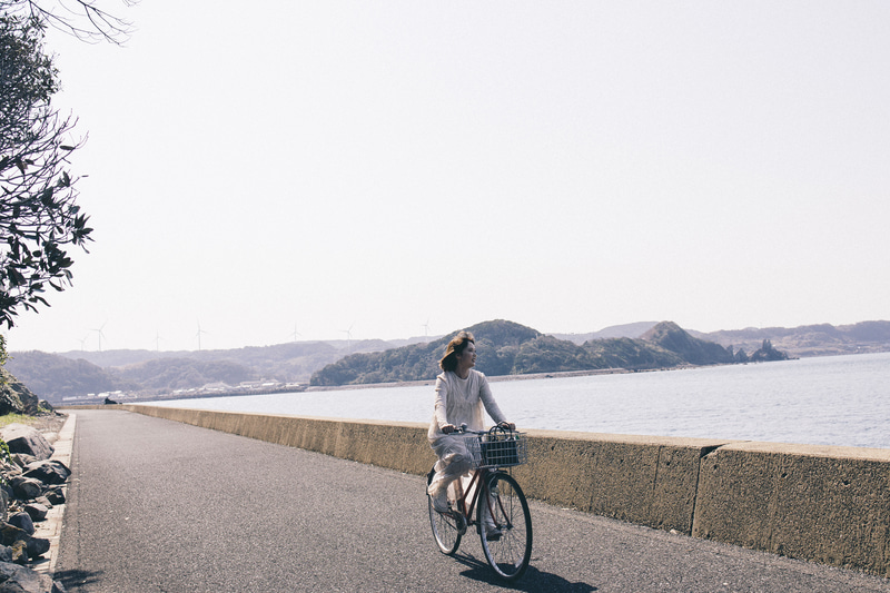 この島で一番撮りたかった海辺を自転車で走るシーン。早歩きで動きながら撮影したが、瞳トラッキングのお陰で動きながらでも、瞬時にピントを合わせることができた<br><span class="fnt-85">EOS R8／RF35mm F1.8 MACRO IS STM／35mm／マニュアル露出（F4.5、1/2,000秒）／ISO 200／WB：オート</span>