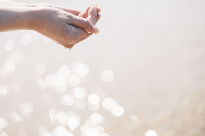 14時頃、光が反射して水がキラキラとしていた。水がこぼれ落ちる瞬間を最高約40コマ/秒の高速連写で撮影。F1.8のキラキラした乱反射の玉ボケが、水をすくう手やこぼれる滴を浮かび上がらせてくれる<br><span class="fnt-85">EOS R8／RF50mm F1.8 STM／50mm／マニュアル露出（F1.8、1/8,000秒）／ISO 200／WB：オート</span>