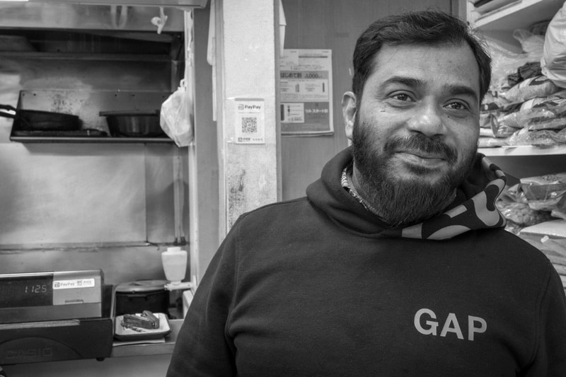 下町でハラールなお店を見つけました。店主を撮影させていただいたのですが、光のメリハリが弱い蛍光灯下でも良い感じに描写します。<br>PENTAX K-3 Mark III Monochrome／HD PENTAX-DA 20-40mmF2.8-4ED Limited DC WR／絞り優先AE（29mm・F10・1/30秒）／ISO 3200