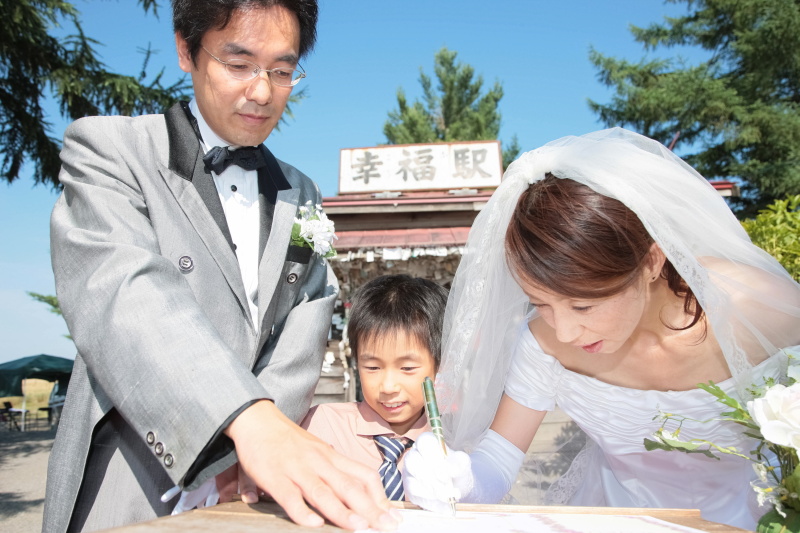 森さんご夫妻とご子息。記念証を描きながらのひとコマ