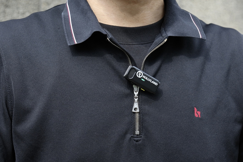 実際に男性の胸元にTXを取り付けた例。48×21.5×10mmという小ささだが、ロゴの主張はちょっと大きめか？（笑）