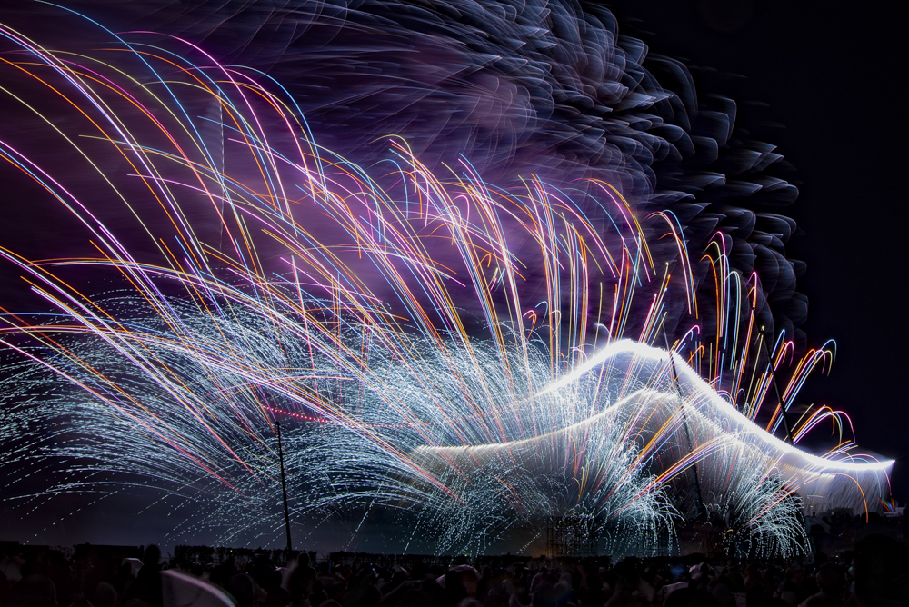 ナイアガラは最も明るい花火のひとつ。2秒以上露光すると露出オーバーになる。BULBで1秒半経ったらレンズの前に黒布を被せてナイアガラが終わるまで待つ。ナイアガラが終わったら黒布を外して背景の花火を写す（撮影：金武 武）<br><span class="fnt-85">D600／AF-S NIKKOR 18-35mm f/3.5-4.5G ED／18mm／マニュアル露出（76秒、F13）／ISO 100</span>