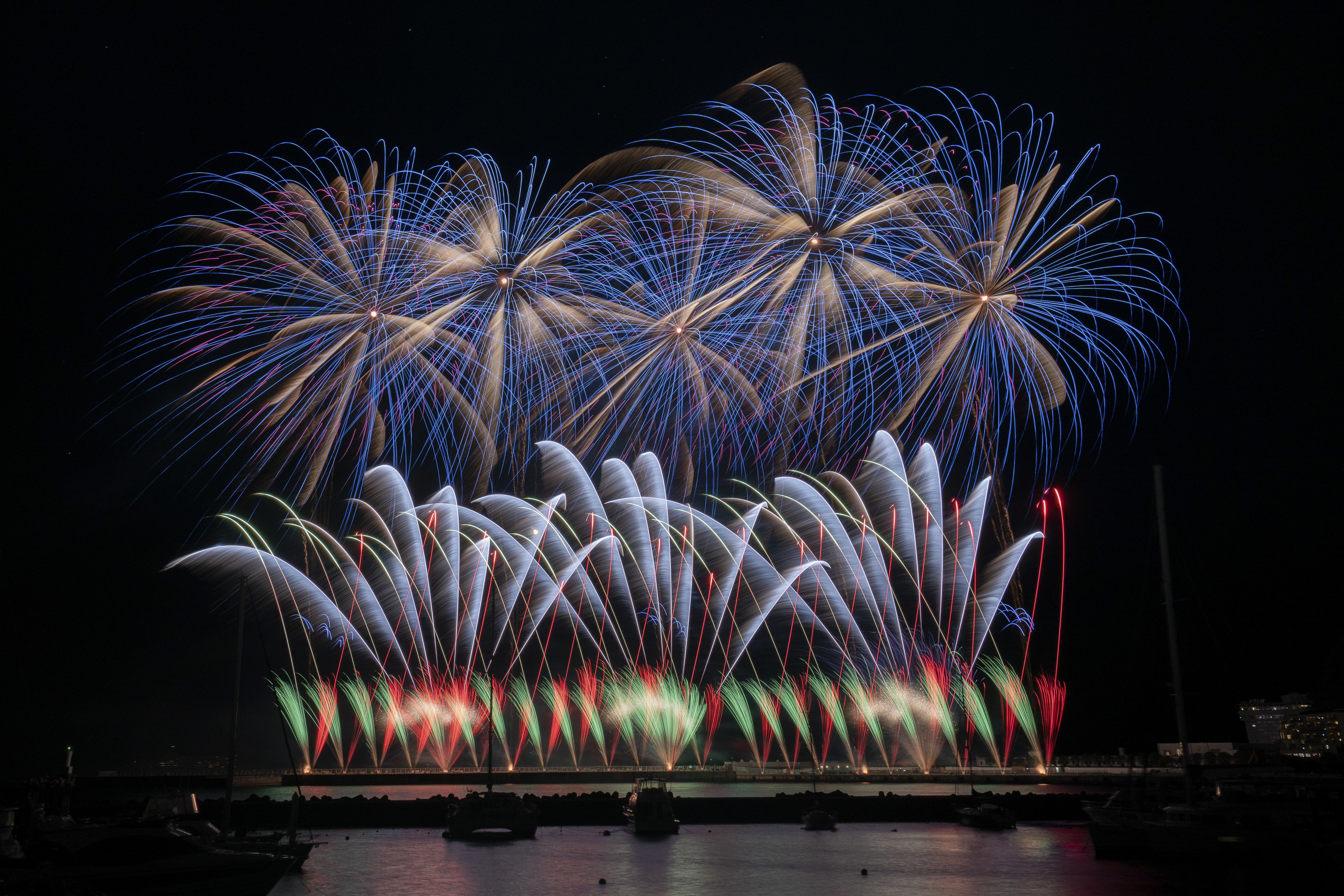 激しいデジタルスターマイン。明るい噴出花火が次々打ち上がり重なってくる。一ヶ所に沢山の花火が写ると露出オーバーになる。上空に一列、低空に一列の花火が開花したら撮り終わればよい（撮影：金武 武）<br><span class="fnt-85">α7 IV／Vario-Tessar T＊ FE 16-35mm F4 ZA OSS／26mm／マニュアル露出（14.0秒、F11）／ISO 200</span>