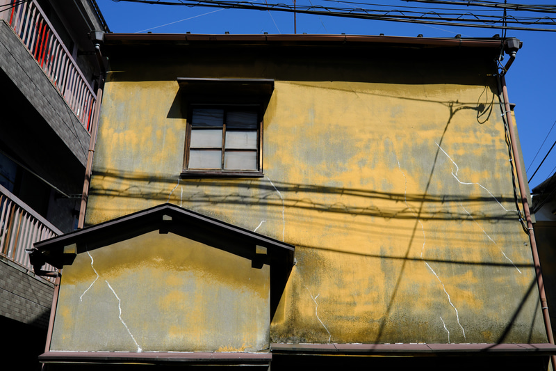 くすんだ黄色い壁の色の年季の入った家に出会いましたが、フィルムシュミレーションをVelviaにして、少々色を盛ってポップな感じにしました。<br>FUJIFILM X100V／マニュアル露出（F5.6・1/1,000秒）／ISO 160／Velvia
