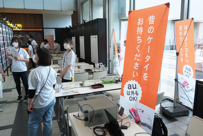 KDDIの「おもいでケータイ再起動」サービスの特設コーナーも併設。動かなくなった古い携帯電話を専用機器で再起動。思い出の写真をプリントしてくれる。au以外のモデルも対象となっている