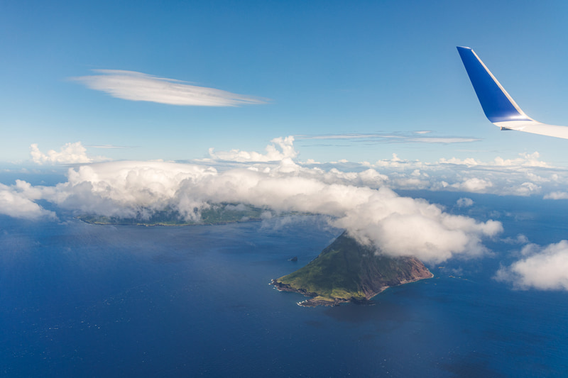 羽田空港から約1時間のフライトで八丈島に到着する。島の北西には、八丈小島（写真手前）という無人島もあり、八丈島から見えるこの島のシルエットも美しい<br><span class="fnt-85">EOS R8／RF24-105mm F4 L IS USM／29mm／絞り優先AE（F5.6、1/640秒、±0EV）／ISO 200／WB：オート</span>