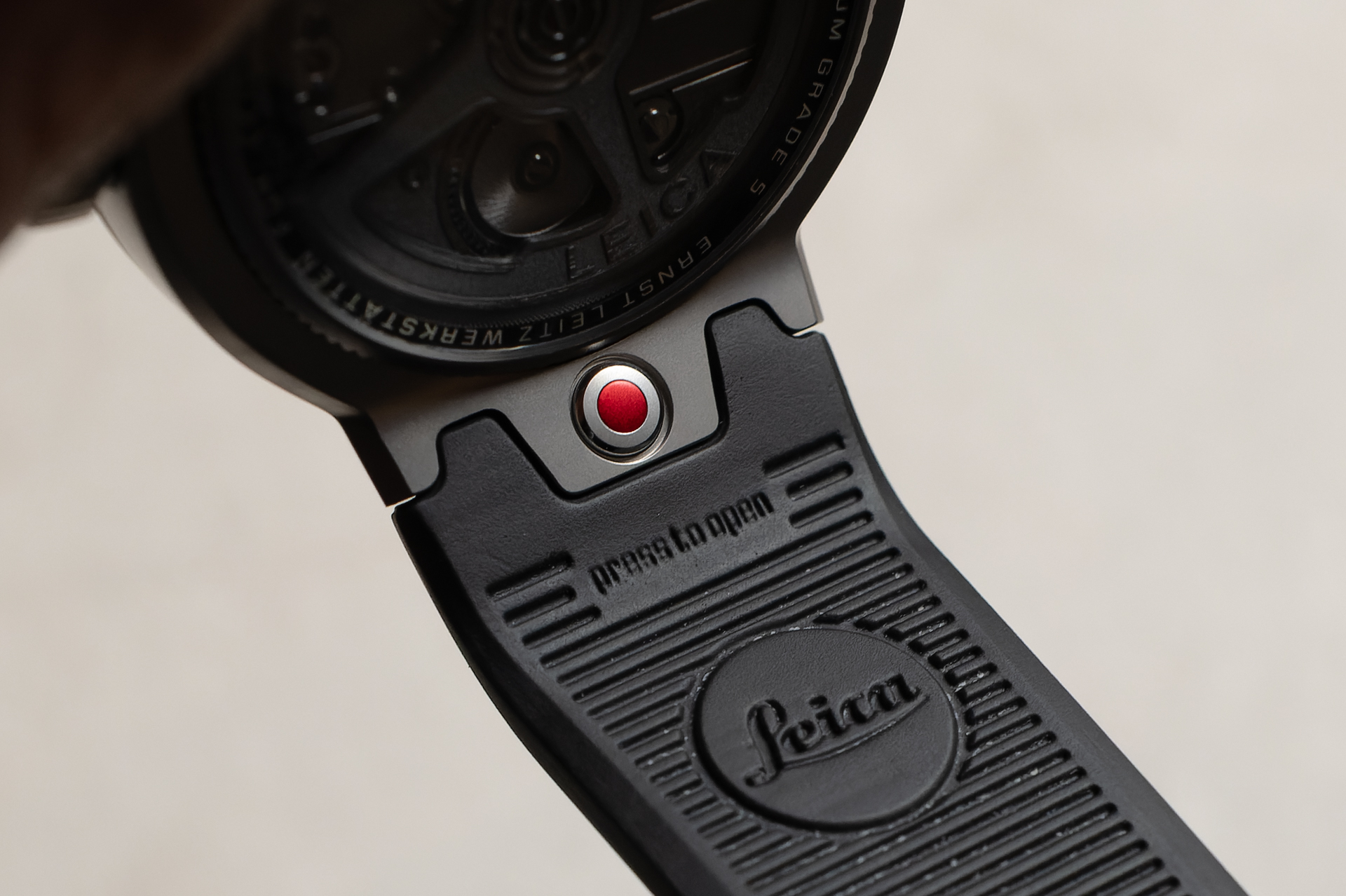 裏側のストラップ着脱ボタン。レンズ着脱ボタンがモチーフ