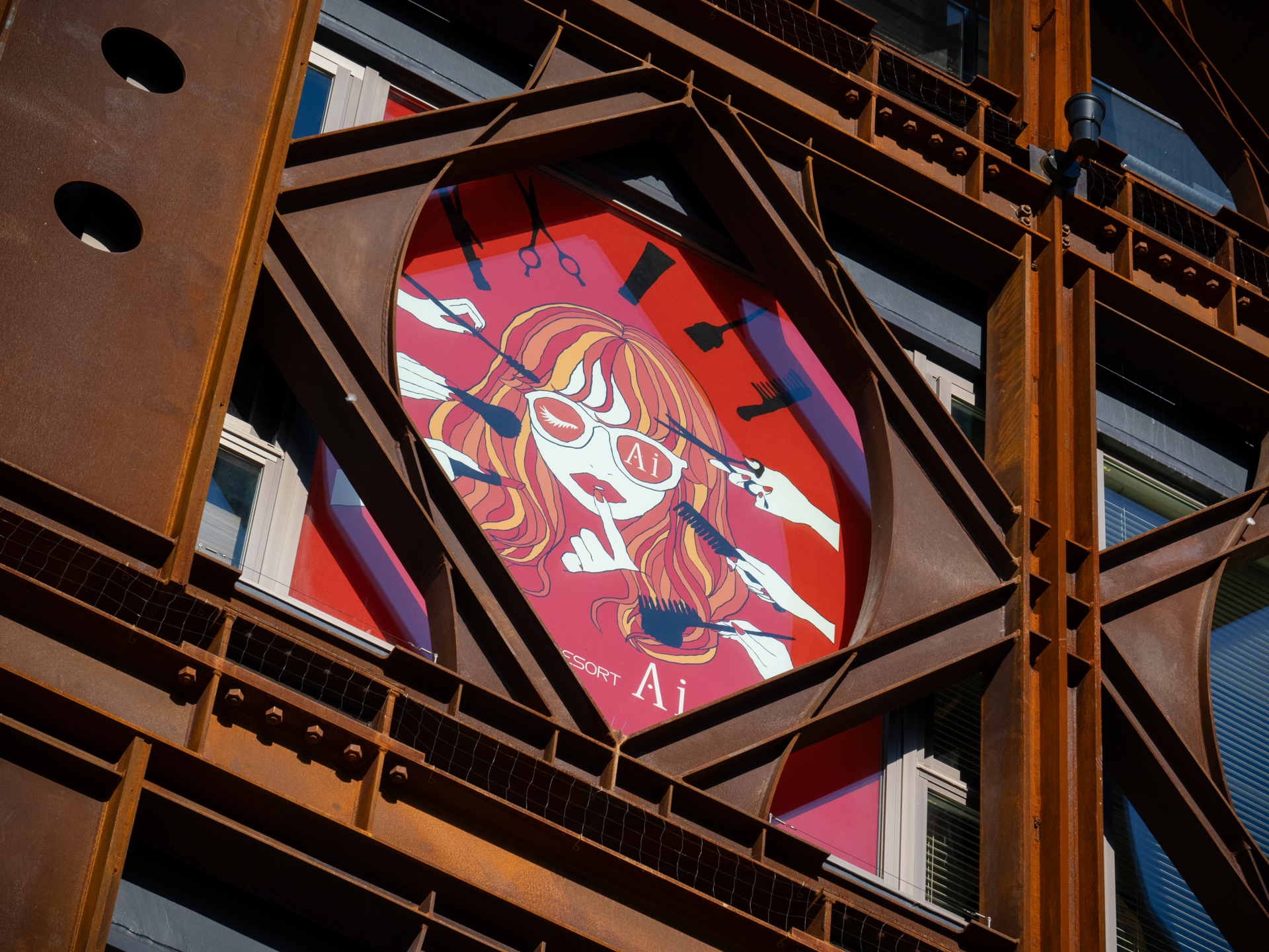 耐震鉄骨が剥き出しのビル。筆者の好きな錆、ボルトが良い感じに中のイラストの色と呼応しております。これは意図的に塗装をしないんでしょうね。今度きちんと撮影しておこう<br>LUMIX G9PROII／LEICA DG VARIO-ELMARIT 12-60mm / F2.8-4.0 ASPH. / POWER O.I.S.／絞り優先AE（60mm・F8・1/800秒・-0.7EV）／ISO 400