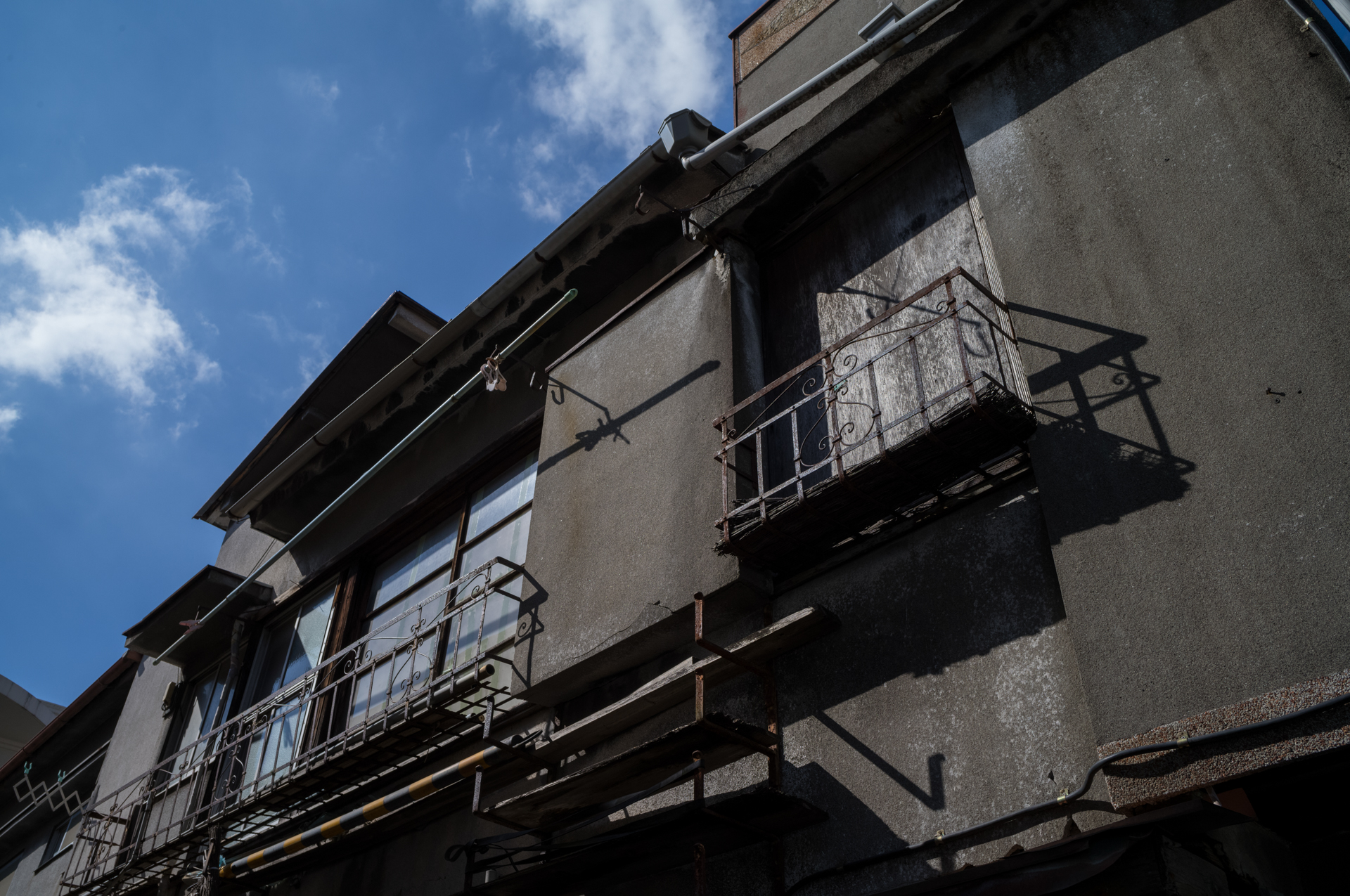 黒くて古い壁のアパート。青空と明暗の差が大きいですが、階調の繋がりがとてもよく感じます。雲の描写も良い感じです<br>ライカM11-P／NOKTON Vintage Line 28mm F1.5 Aspherical／マニュアル（F8・1/1,000秒・±0EV）／ISO 400