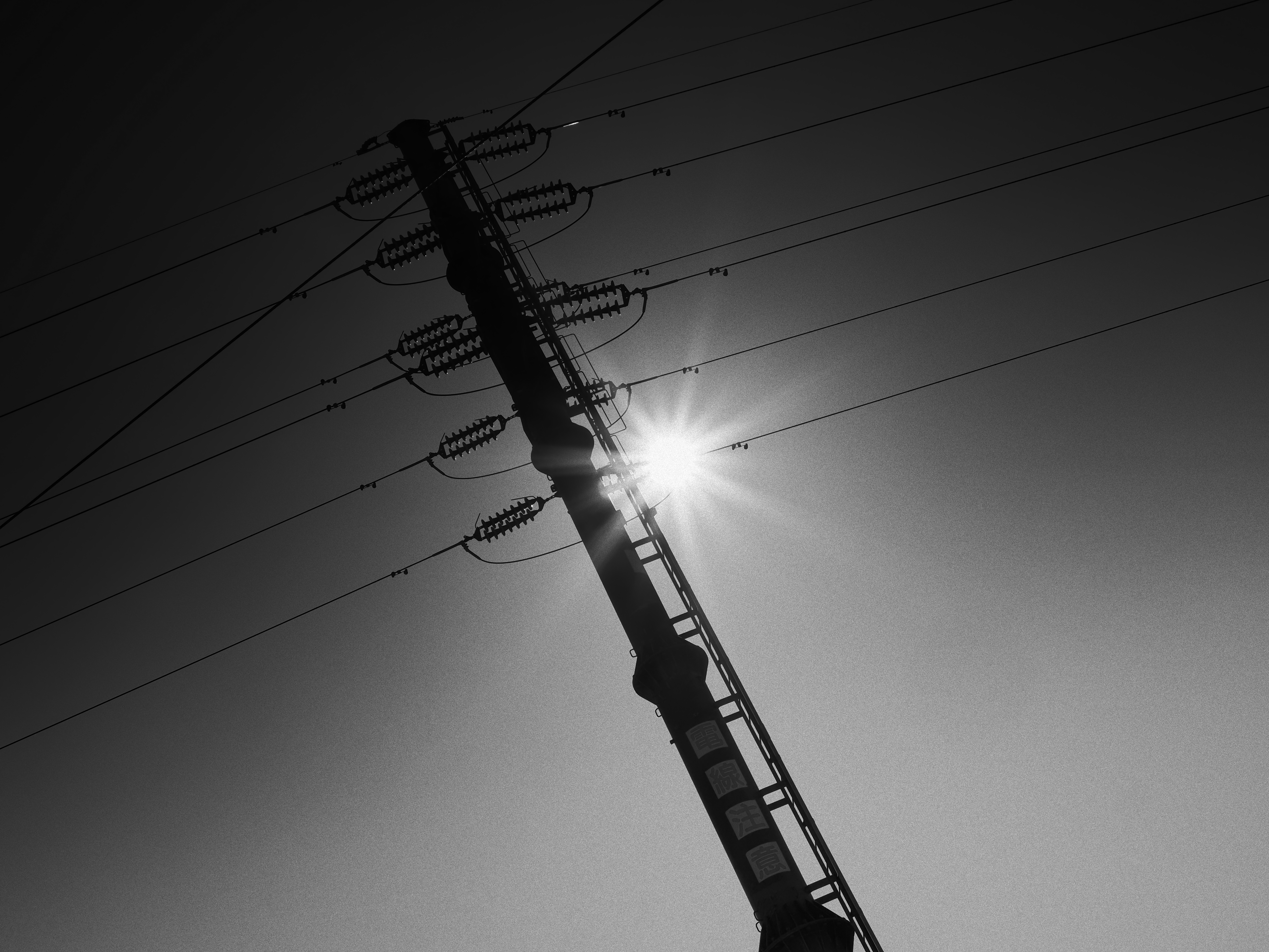 あれこれGND効果を試したんですが、そうだ、モノクロだぜということで太陽を入れ込んだ状態で撮影しました。粒状は中に設定してみました。ND8で整いました。「1970年代の地平」などとタイトル付けたくなりません？<br><span class="fnt-85">OM-1 Mark II／M.ZUIKO DIGITAL 25mm F1.8／25mm（50mm相当）／絞り優先AE（1/800秒、F11、-0.7EV）／ISO 200</span>