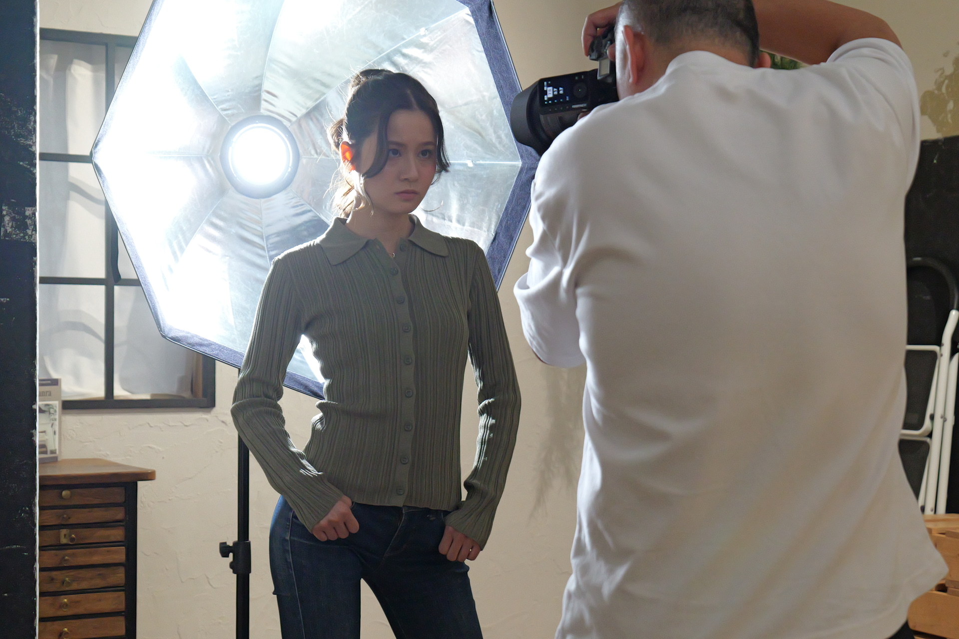 撮影風景。モデルの真後ろにディフューザーを外した「Profoto ソフトボックス 3’Octa Silver」をセット。ここからさらに手前に反射板（白い発泡ボード）を2枚挟み込むように入れ込み、背後からの逆光をモデルの顔に回し込んでいった。ライトはB10Xを使用した