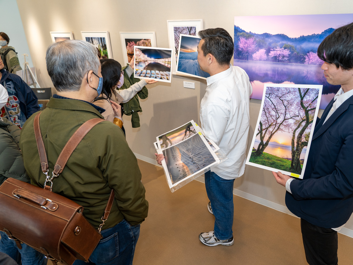 在廊中、本間氏への質問に集まった来場者に撮影テクニックや用紙の選び方について説明する一幕も