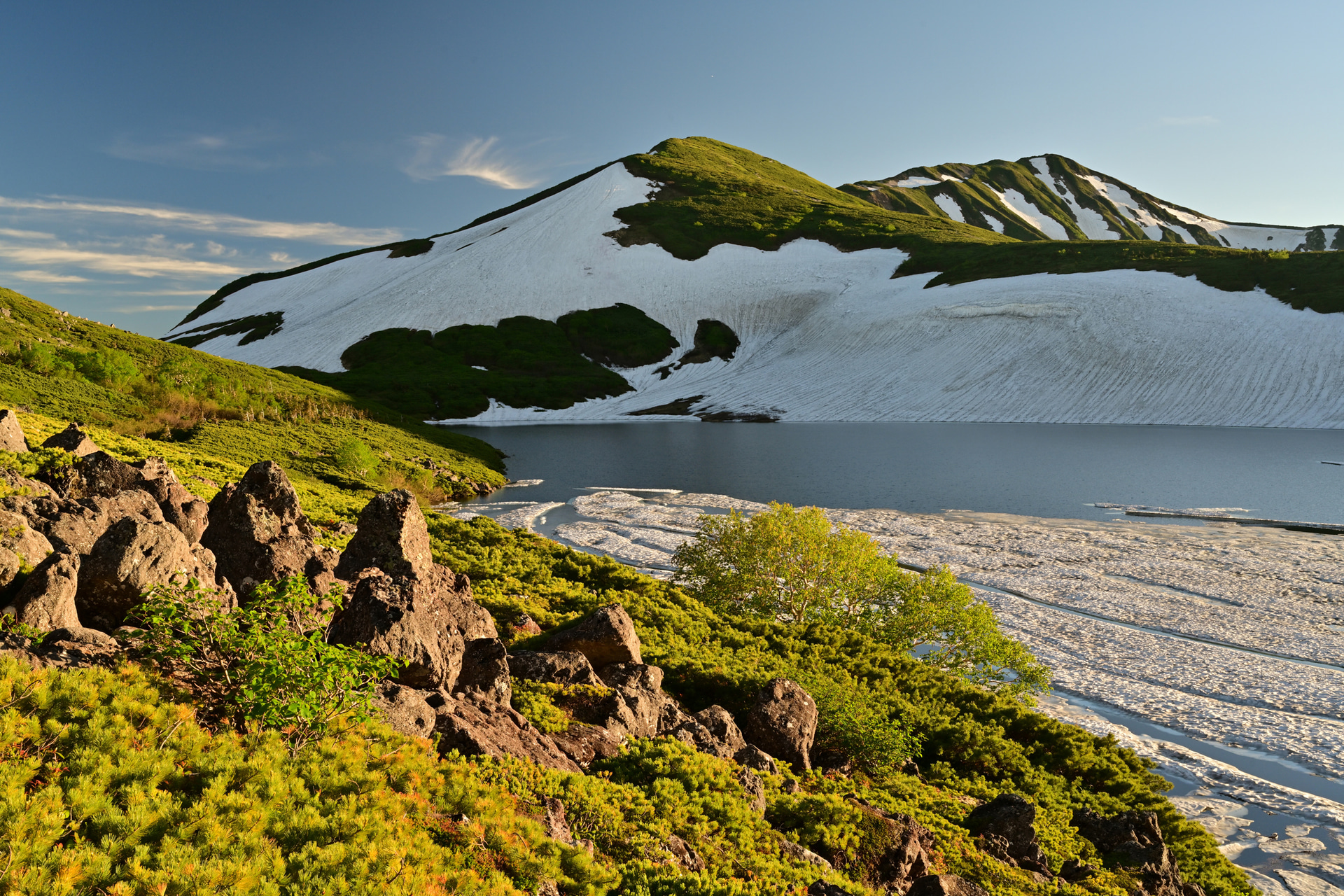 解氷する白馬大池の畔で三脚を立てて、夕焼けするまでじっくりと待って撮影した。手前から奥までパンフォーカスで写したいので、絞りはF14まで絞り込んだ。構図を決めて、良い光を待てるのは三脚があるからこそだ<br><span class="fnt-85">ニコン Z 7／NIKKOR Z 24-70mm f/2.8 S／34mm／マニュアル露出（F14、1/40秒）／ISO 200／WB：曇天</span>