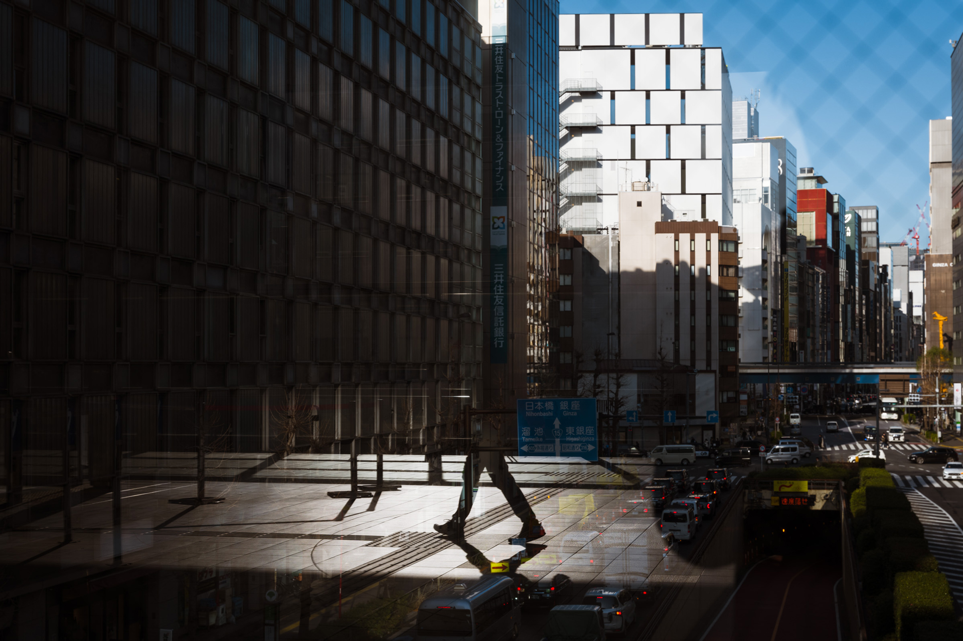 左側のビルの窓と、右側に映るワイヤーガラスの網目模様との対比が面白く感じて撮影した。ガラスへの映り込みが像の層を生み出す。3層目には歩く人の影が入って、ちょうど良いアクセントになった<br><span class="fnt-85">ライカSL3／ライカ バリオ・エルマリートSL f2.8/24-70mm ASPH.／50mm／マニュアル露出（F5.6、1/640秒）／ISO 100／WB：オート</span>