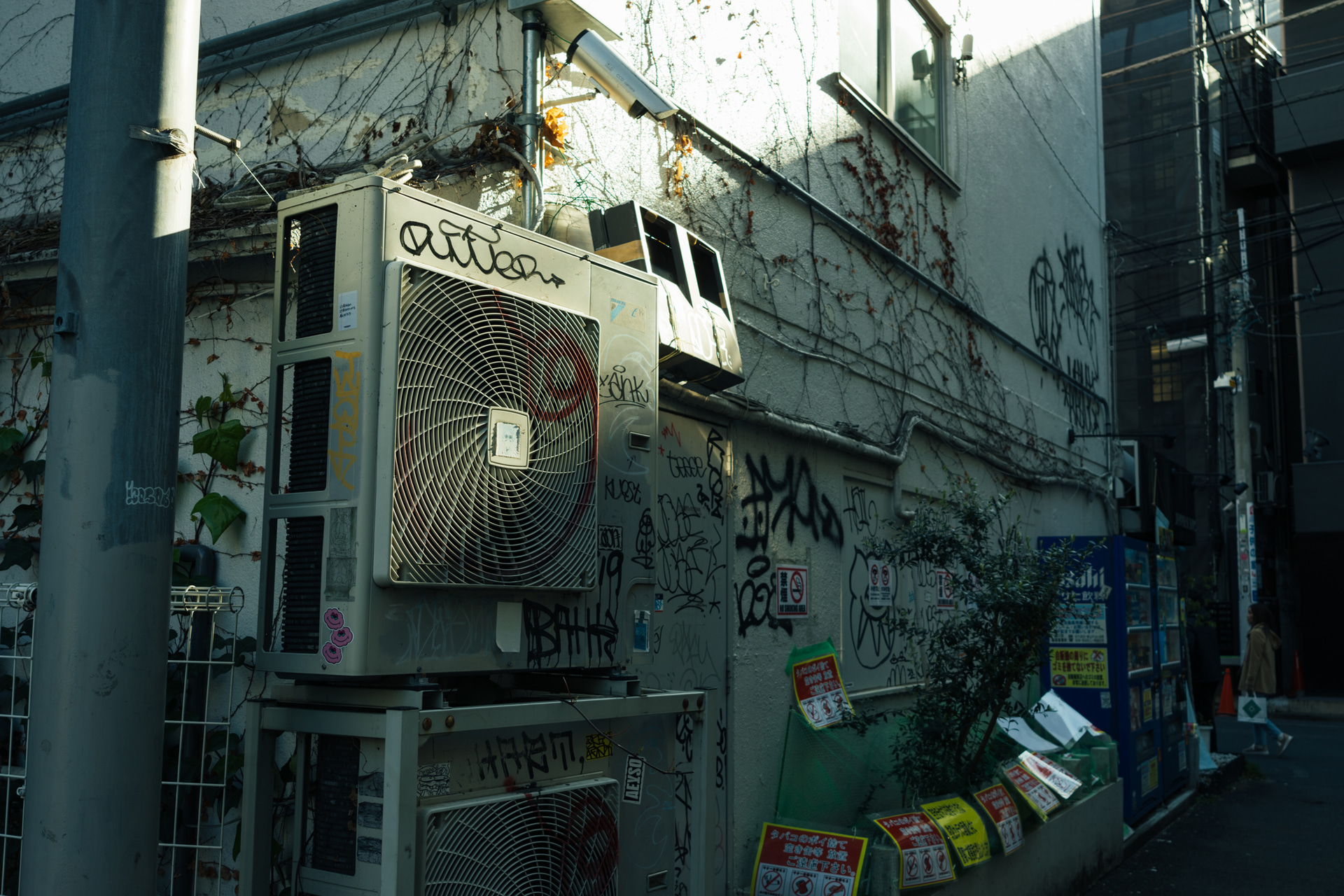 グラフィティだらけの室外機のストリート感を35mmで周りの質感ごと捉えた。コントラストをマイナスにして暗部がつぶれ過ぎないように気を付けている<br><span class="fnt-85">キヤノン EOS R8／RF24-50mm F4.5-6.3 IS STM／35mm／絞り優先AE（F6.3、1/125秒、－0.7EV）／ISO 100／WB：6,600K（B2＋G2）</span>