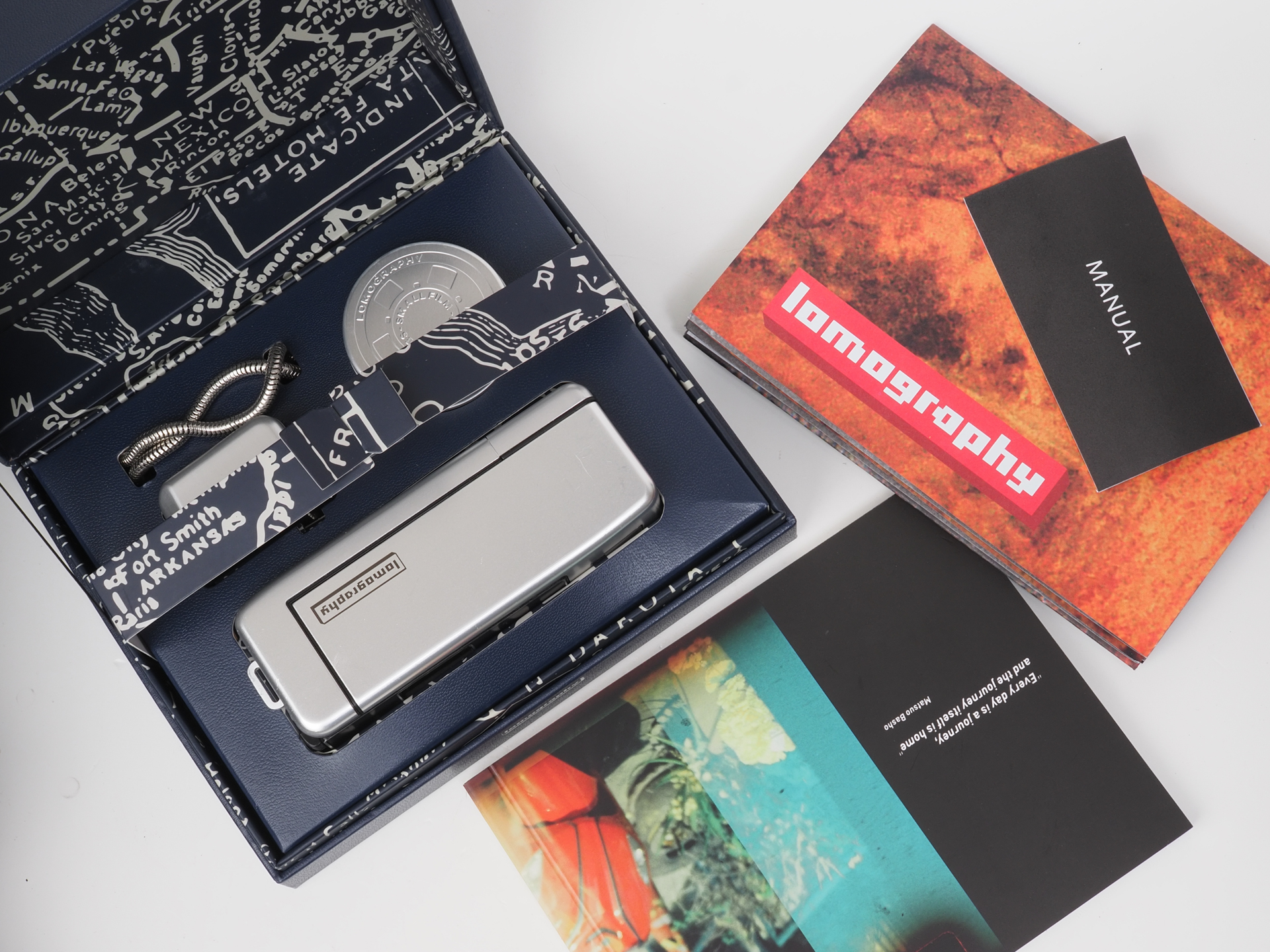 箱を開けるとカメラ本体、着脱式フラッシュ、ストラップ、フラッシュ用フィルター、サンプル写真の冊子、ポスター、マニュアルが同梱されています