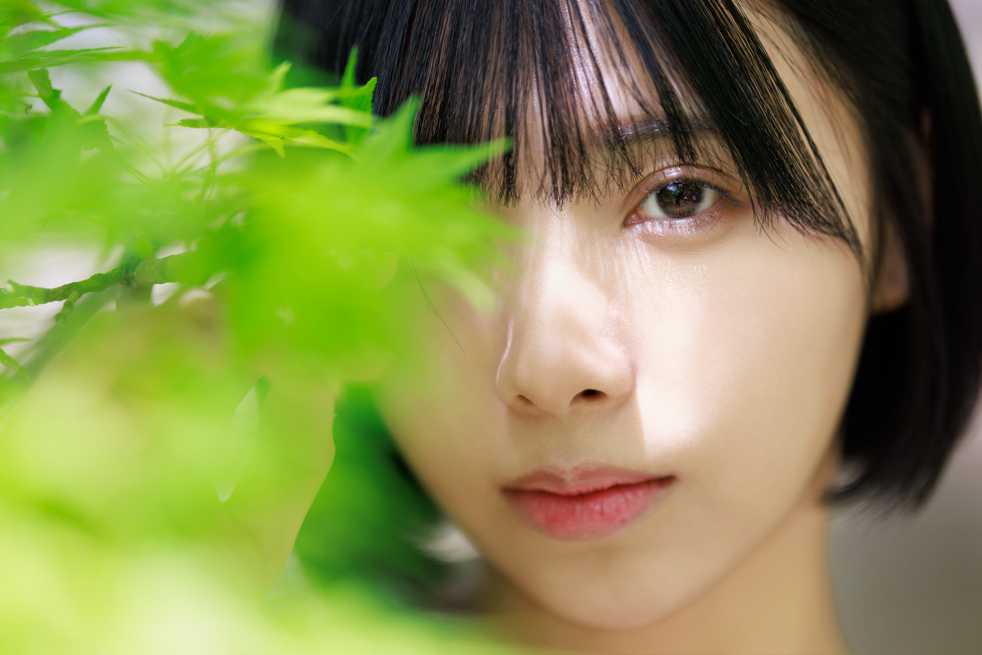 最短撮影距離の70cmまで近づいて絵作りを行った。右目を隠した前ボケの効果もあって、左目の印象が強まっている。緑色の発色も肌を美しく見せてくれる<br><span class="fnt-85">キヤノン EOS R5／RF135mm F1.8 L IS USM／135mm／マニュアル露出（F1.8、1/500秒）／ISO 100／WB：オート</span>