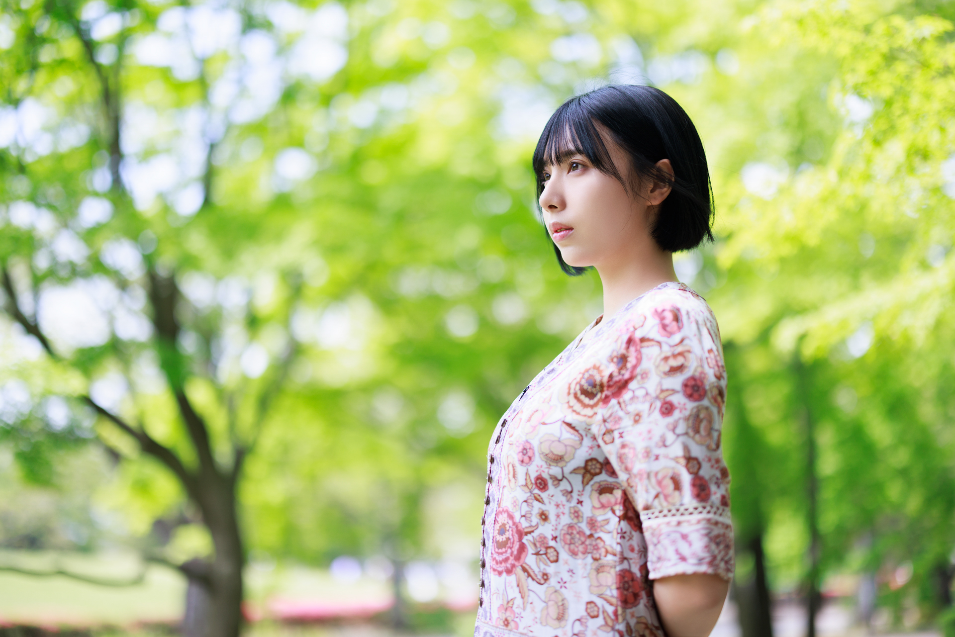 モデルの周囲に余計な被写体が入り過ぎる印象。背景にある濃い茶色の枝がぼけ切れずにはっきり見えて主張しているため、モデルが浮き立つ力は弱い