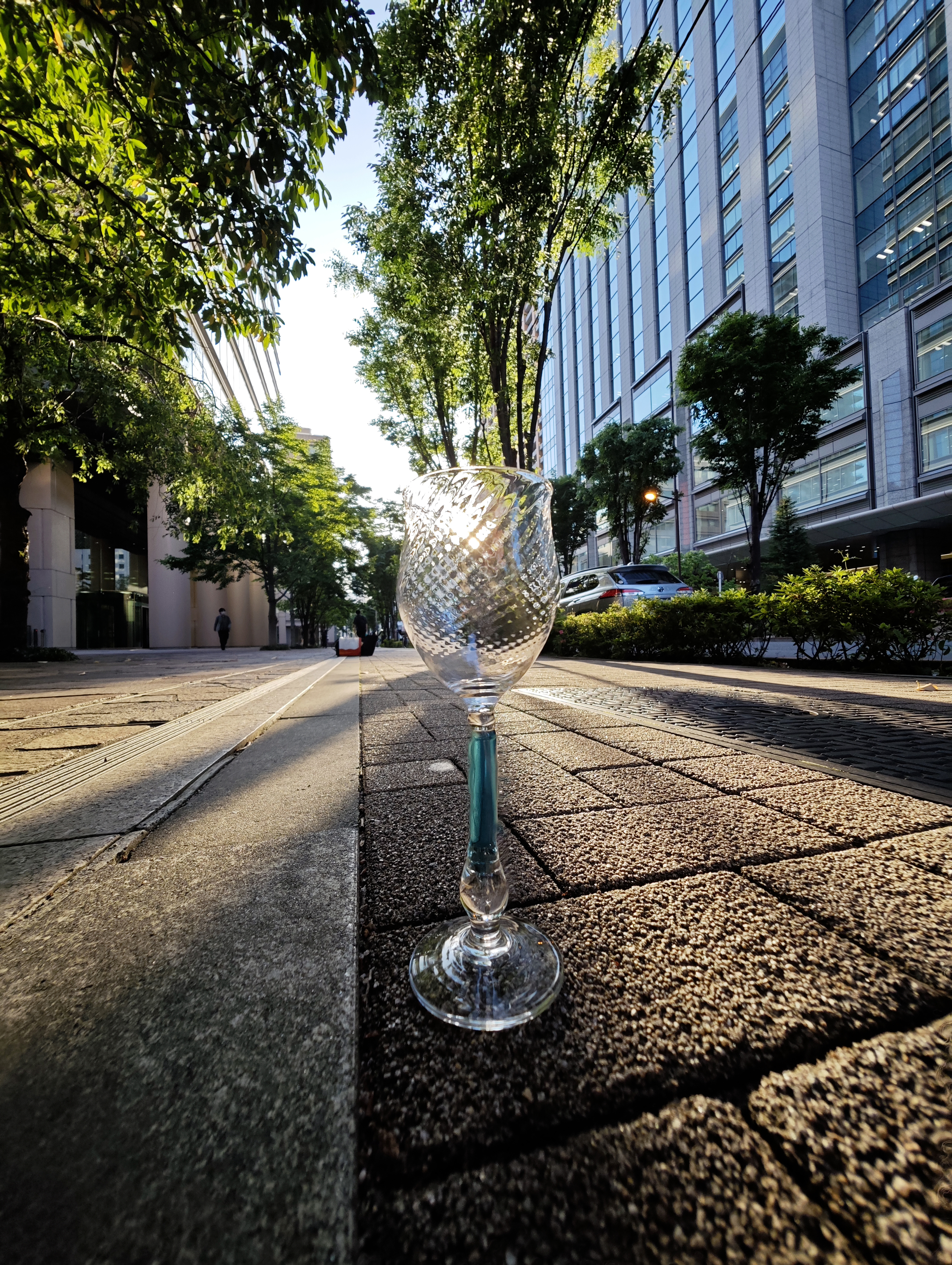 路面に置いたグラスに太陽を重ねて、12mmで撮影した。奥行きのある表現は超広角レンズならでは。個性的な4つのレンズが表現の幅を広げてくれる<br><span class="fnt-85">12mm相当／絞り優先AE（F1.8、1/429秒、±0EV）／ISO 50／WB：オート</span>