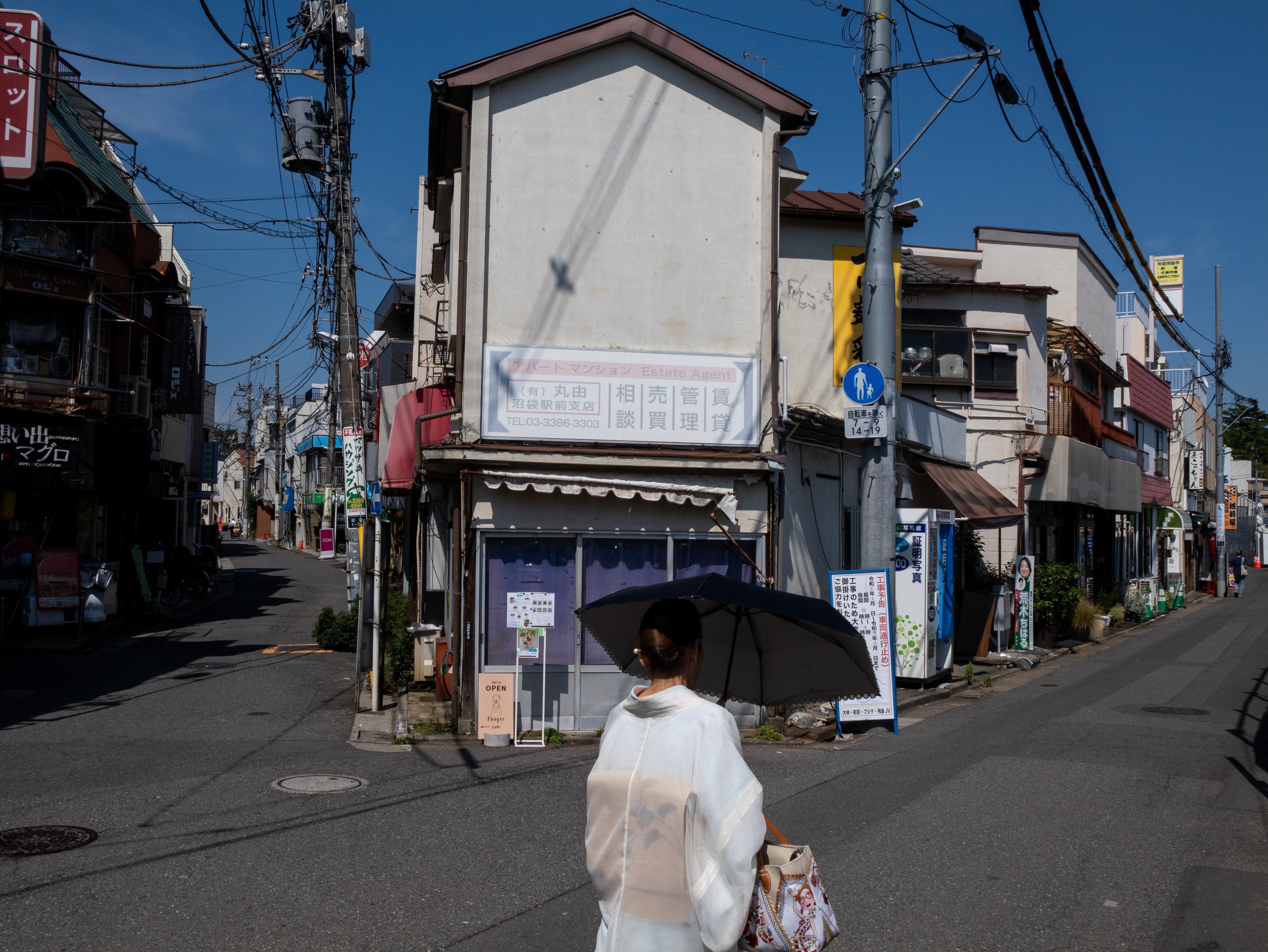街角。カメラを頭上に上げて撮影したスナップです。まったくの勘というか偶然だけど、フレームに収まりました。こういうのはスポーツ撮影みたいで楽しいですね。<br><span class="fnt-85">パナソニック LUMIX G9PROII／ライカ バリオエルマー14-50mm F3.8-5.6 ASPH.／16mm（32mm相当）／絞り優先AE（1/2,500秒、F9.0、−0.7EV）／ISO 400</span>