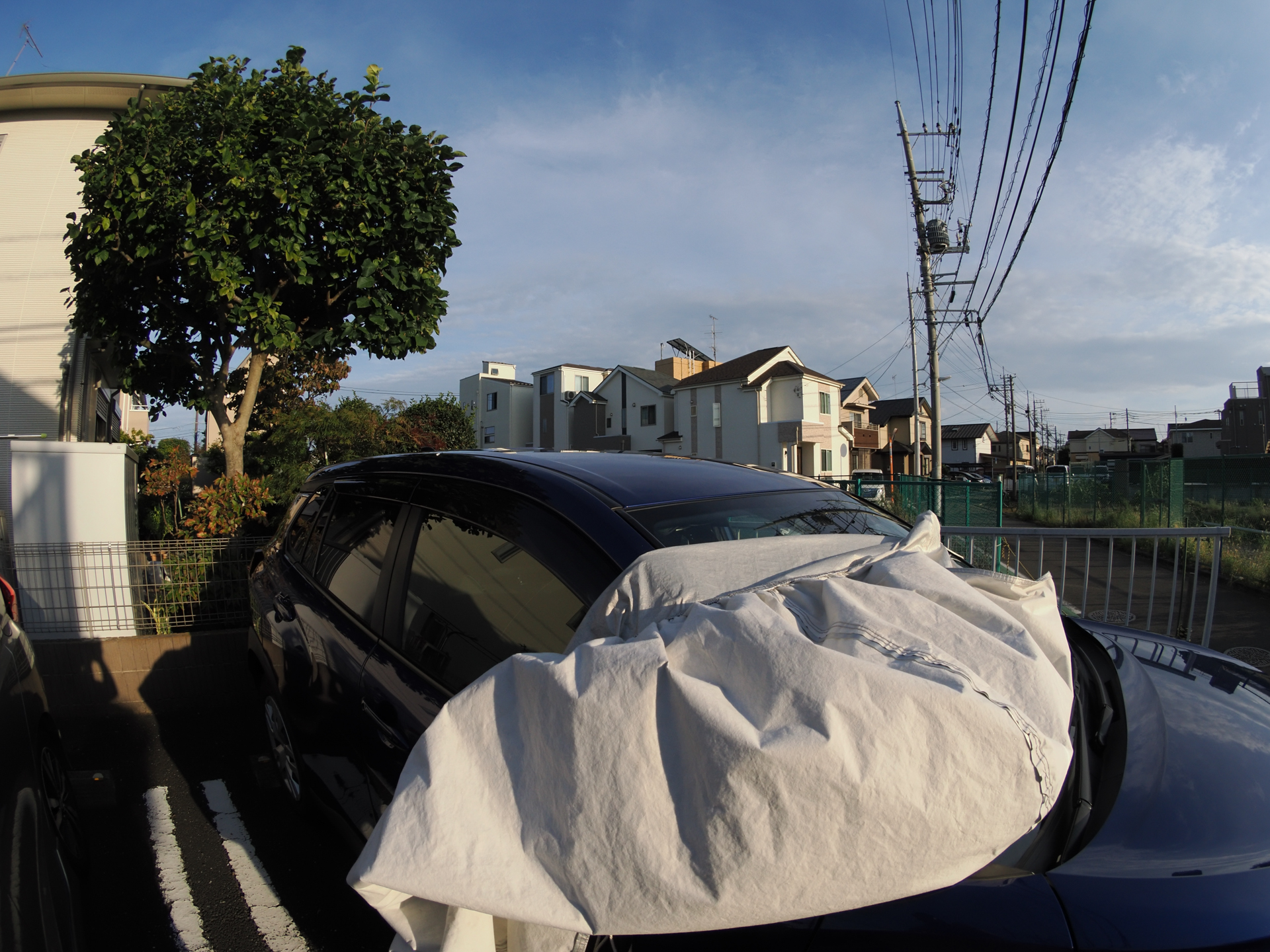 強い風の日で自動車のカバーがめくれてしいました。それだけなんですが撮影します。なんか魚眼で撮影しますとヘンでよくないですか。<br><span class="fnt-85">OM SYSTEM OM-1／ZUIKO DIGITAL ED 8mm F3.5 Fisheye／8mm（16mm相当）／絞り優先AE（1/1,250秒、F8.0、−1.0EV）／ISO 400</span>