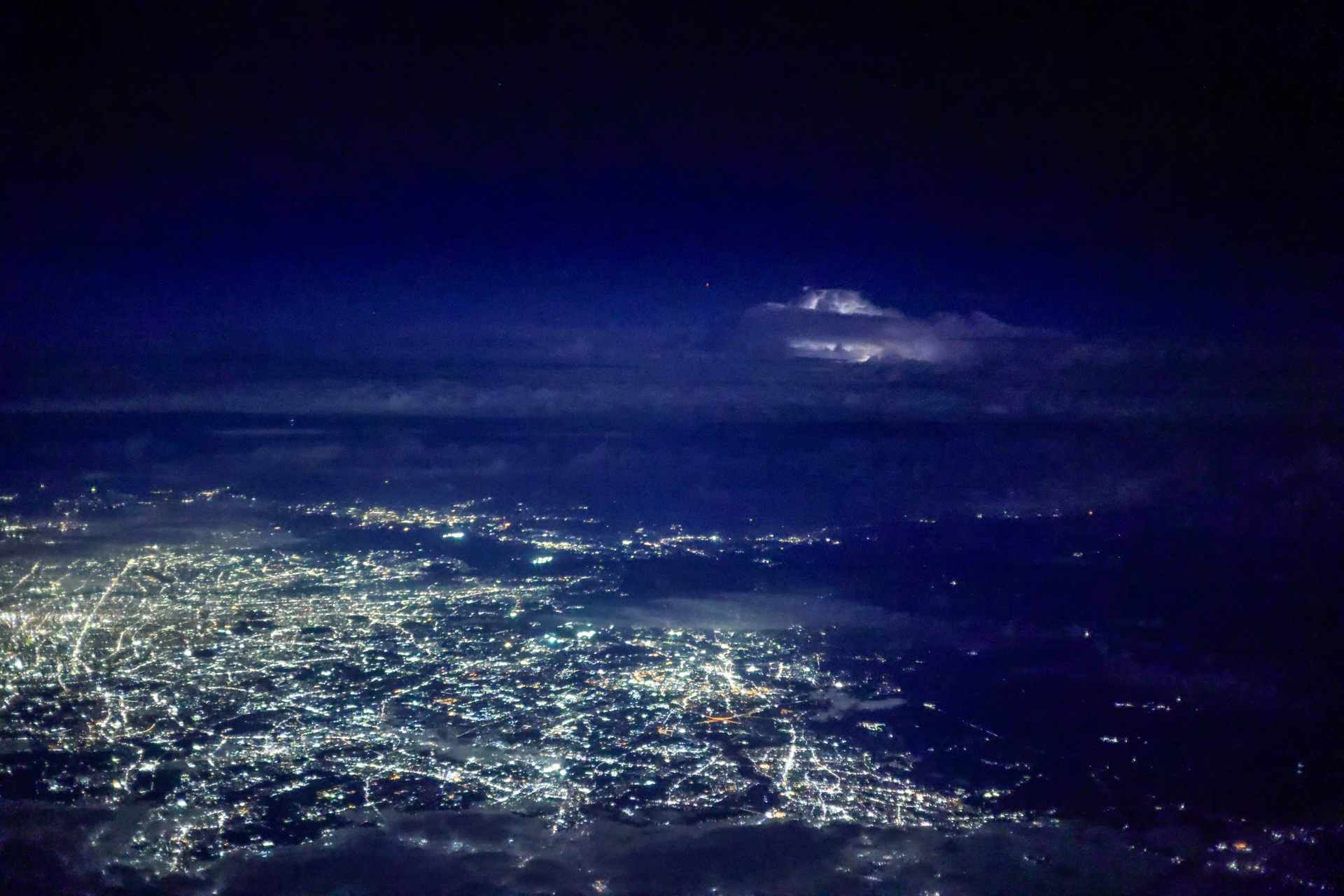 夜間飛行中に街灯りの奥の空が一瞬光った。雷だ！ 急いで「プリ連続撮影」モードにセットし、稲光を待つ。光った瞬間にシャッターボタンを押せばすべて記録されていた。30コマ/秒の撮影なので、大容量のカードがあった方が安心だ<br><span class="fnt-85">キヤノン EOS R5 Mark II／RF50mm F1.8 STM／50mm／絞り優先AE（F1.8、1/40秒、－0.3EV）／ISO 20000／WB：オート（B9）</span>