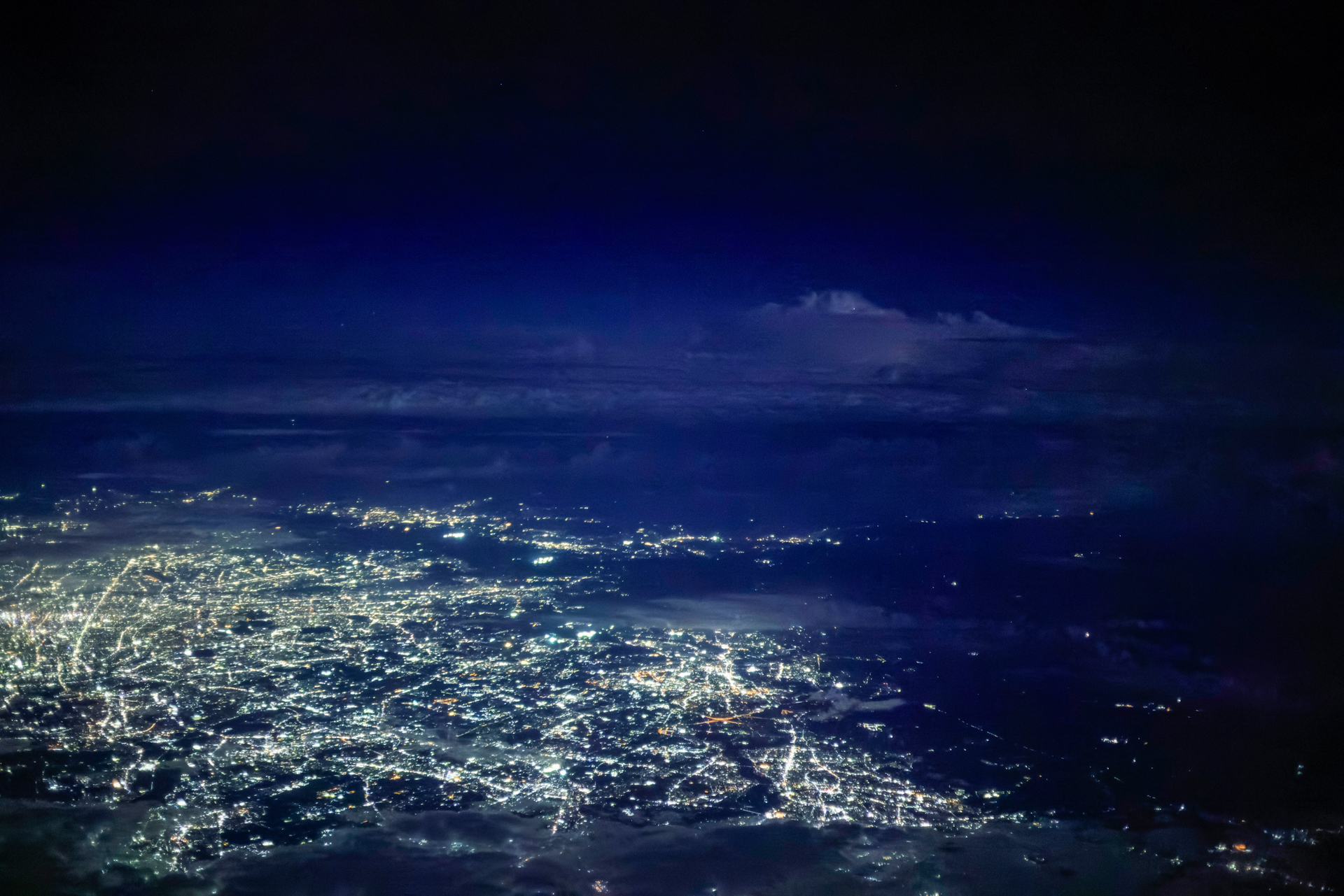 夜間飛行中に街灯りの奥の空が一瞬光った。雷だ！ 急いで「プリ連続撮影」モードにセットし、稲光を待つ。光った瞬間にシャッターボタンを押せばすべて記録されていた。30コマ/秒の撮影なので、大容量のカードがあった方が安心だ<br><span class="fnt-85">キヤノン EOS R5 Mark II／RF50mm F1.8 STM／50mm／絞り優先AE（F1.8、1/40秒、－0.3EV）／ISO 20000／WB：オート（B9）</span>