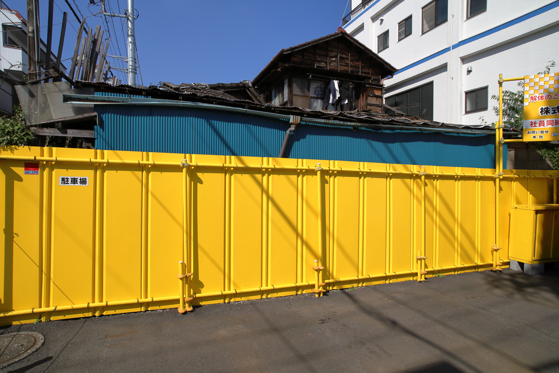 再開発地域。明暗差が大きく、後ろの家屋は再現されないだろうなあと思ったら、ちゃんと写ってますねえ。板塀まで完璧です。<br><span class="fnt-85">キヤノン EOS RP／シグマ 20mm F1.8 EX DG／プログラムAE（1/1,250秒、F13、−0.7EV）／ISO 400</span>