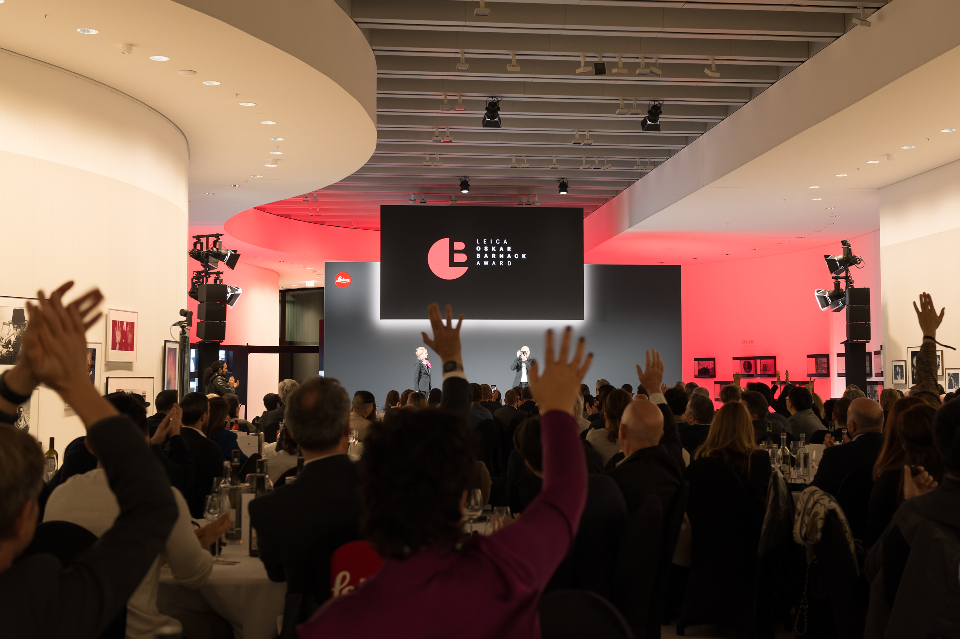 贈られたM型ライカを客席に向ける一幕。ライカM6の使用経験があるという。出席者も喝采