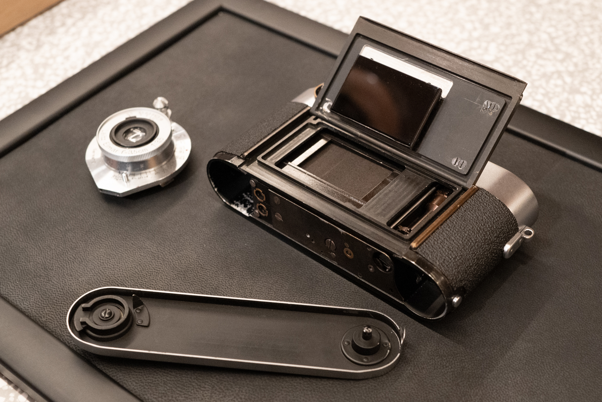 底蓋を外し、裏蓋を開けたところ。ガラス製の圧板は初期のライカM3に通じるが、開口部が小さかったりと相違点が多い。ところどころに残る加工跡も取材陣の萌えポイントだった